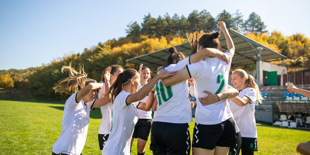 iStock-1218985796_MPL_ST-ZDM Viele Fußballerinnen versammeln sich zu einer Jubeltraube. Bei vielen von ihnen sind man die Trikotnummern auf ihrem Rücken.