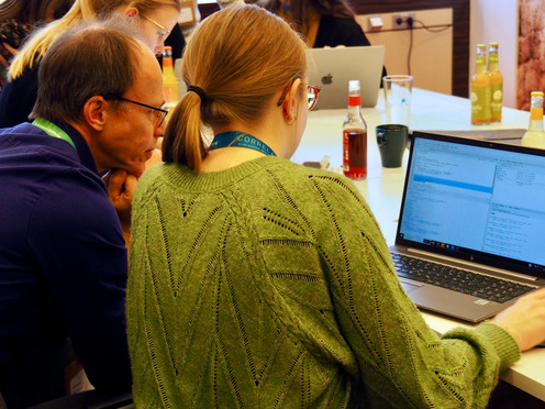 Eine Frau, rechts, und ein Mann, links, sitzen vor einem Laptop. Sie schauen sehr konzentriert auf den Bildschirm des Laptops.