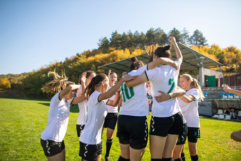 Viele Fußballerinnen versammeln sich zu einer Jubeltraube. Einige Trikotnummern sind auf ihren Rücken zu erkennen.